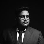 Black and white portrait of a man in a suit with glasses, conveying professionalism and style.