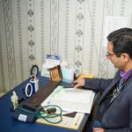 Doctor reviewing medical documents at desk in clinic office.