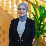 Stylish portrait of a businesswoman in a black suit and hijab, showcasing fashion and confidence.